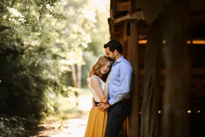 Cozy couple embrace by wooden cabin during engagement session