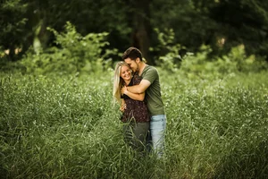 Couple hugging in tall grass field during engagement session