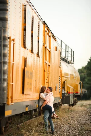 Creative engagement photo by train track with yellow boxcar