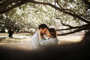Romantic couple under tree in park during engagement session