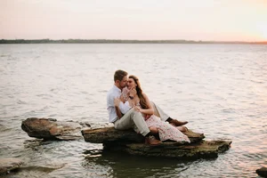 Romantic lakeside engagement photo at sunset on rocks