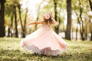 Child spinning in pink dress during outdoor photo session