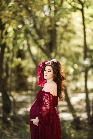 Maternity photoshoot in red lace dress in the woods