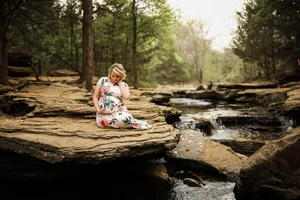 Pregnancy portrait in floral dress by rocky creekside