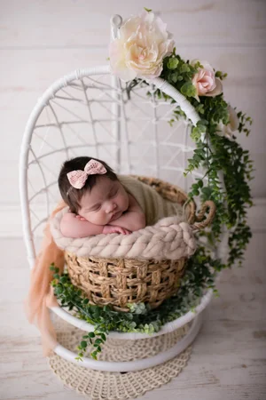 Baby girl in hanging chair with flowers