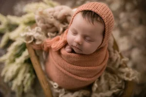 Newborn girl in orange wrap in basket