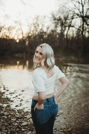 Senior portrait by river at sunset in white top