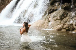 Bride at waterfall during trash the dress session in Denton